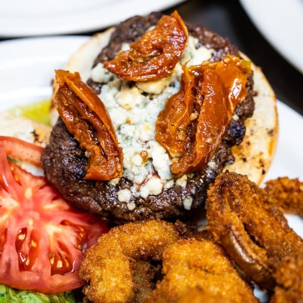 P&G’s American burger with blue cheese, sun-dried tomatoes, lettuce, tomato, and onion rings.